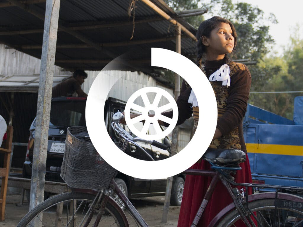 Flicka med en cykel på en innergård i Bangladesh
