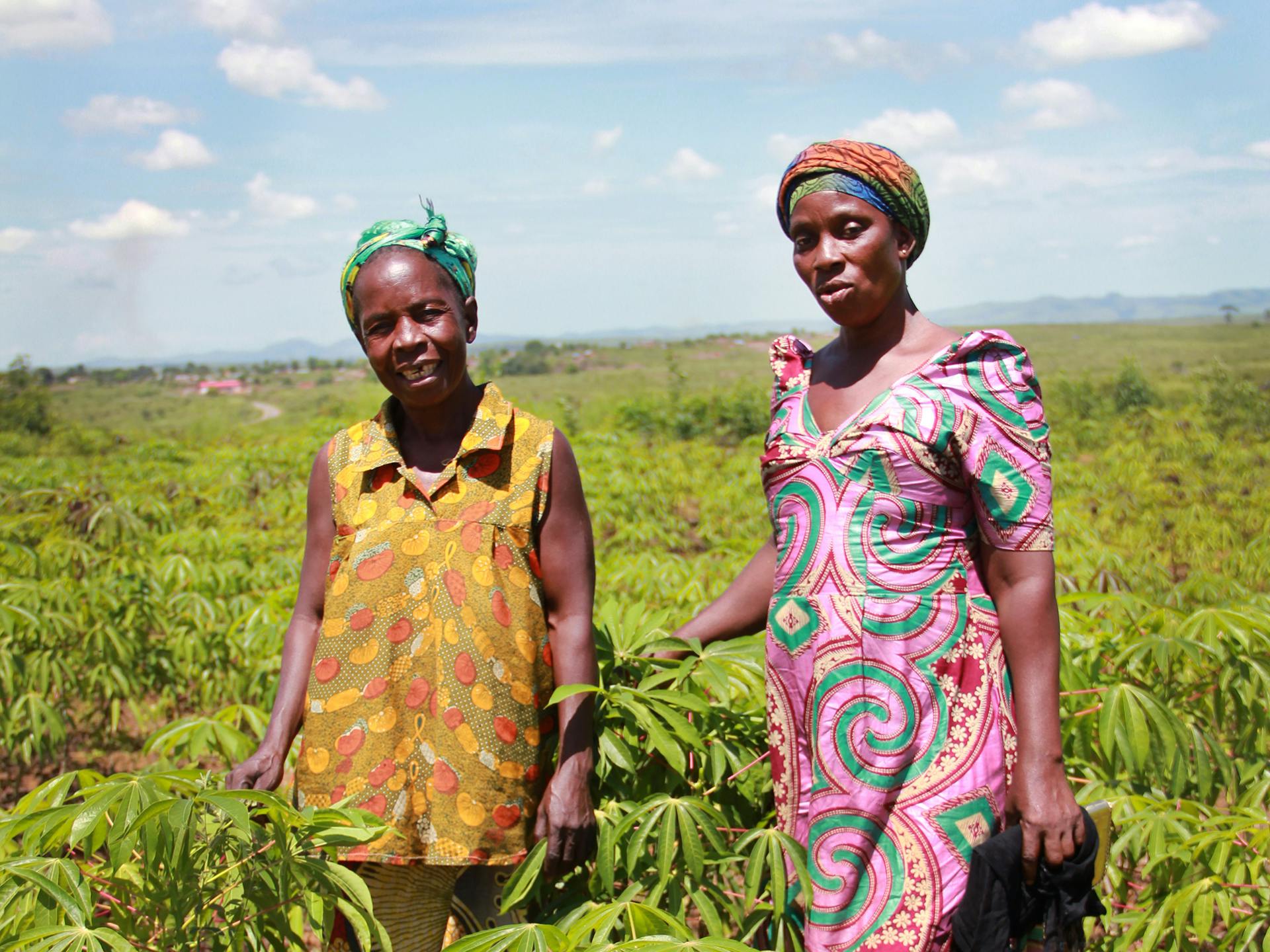 Två kvinnor står i ett stort grönt fält.