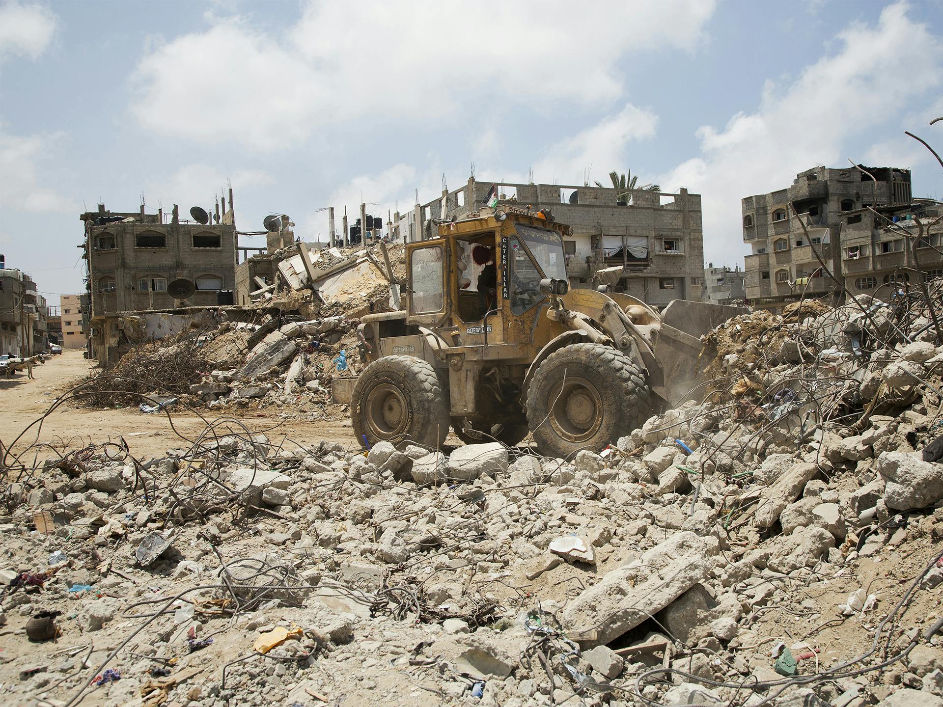Traktor röjer framför bombade bostadshus i Gaza