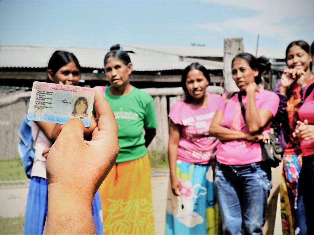 En grupp kvinnor står framför en hand som håller upp ett id-kort.