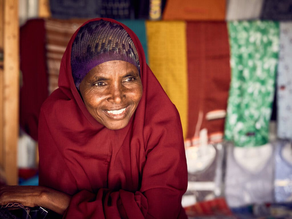 En leende kvinna i vinröd hijab.