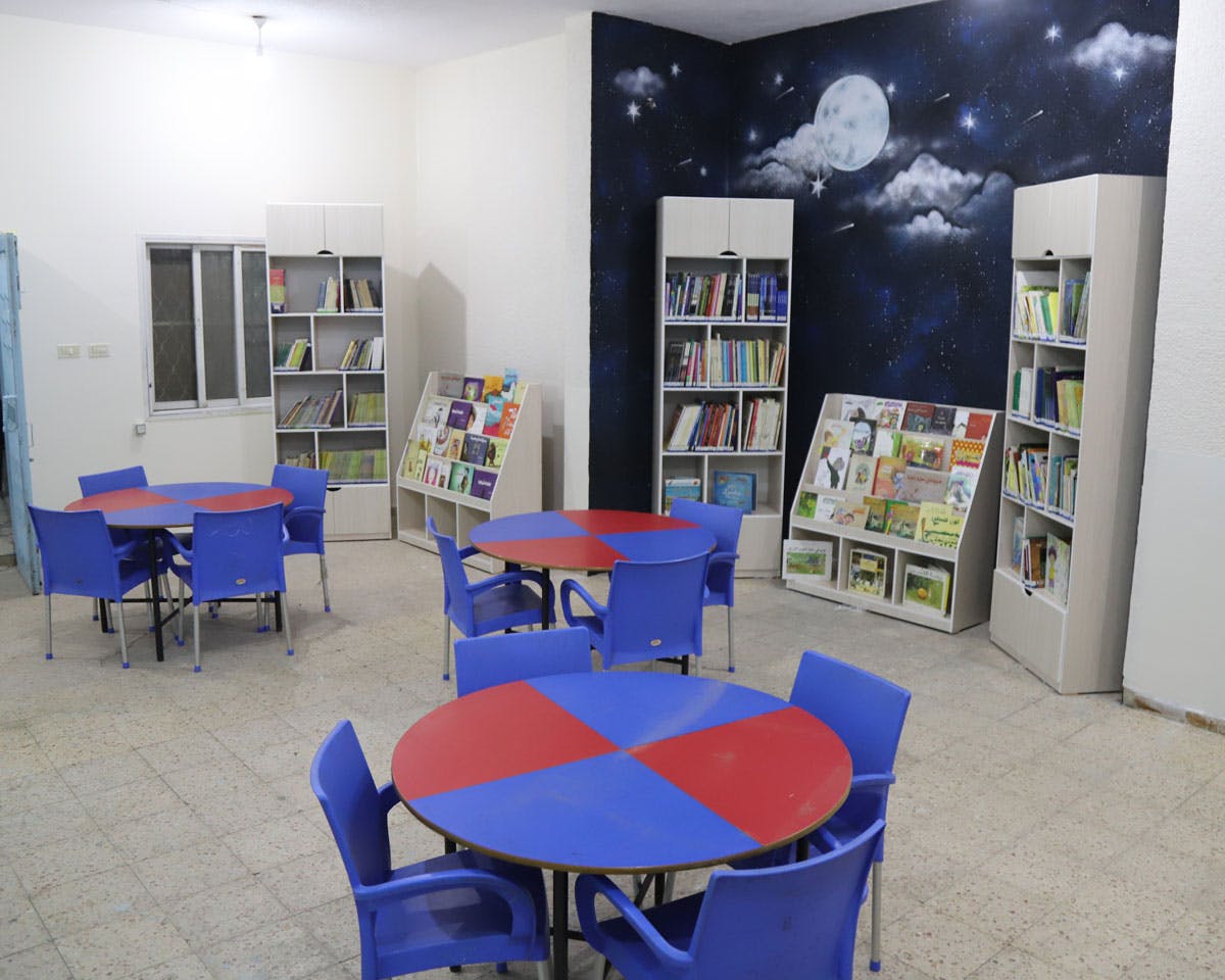 Ett bibliotek med bord och stolar i glada färger och bokhyllor