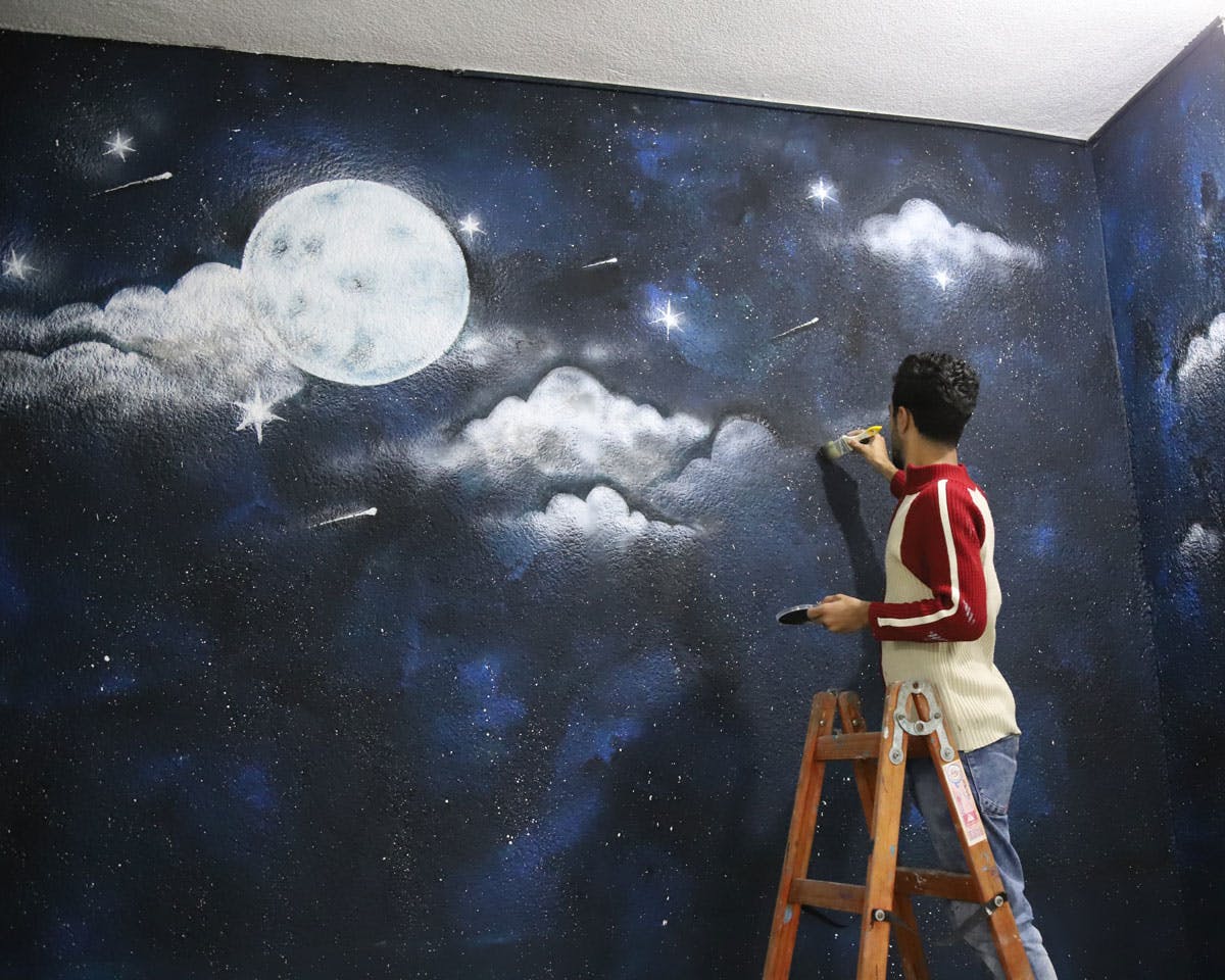 En man på stege målar en vägg som en himmel