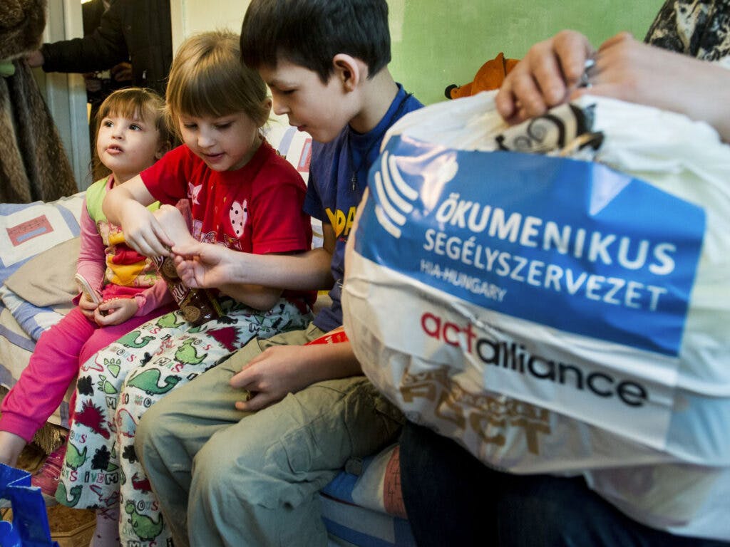 Tre barn som öppnar ett paket med mat.