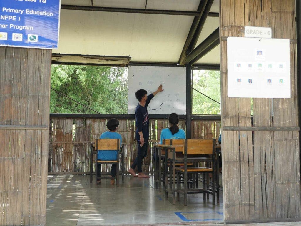 En lärare och elever i en skolbyggnad av bamburör