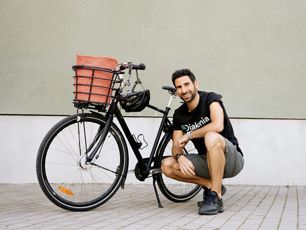Stephan Wilson sitter på huk framför en svart cykel.