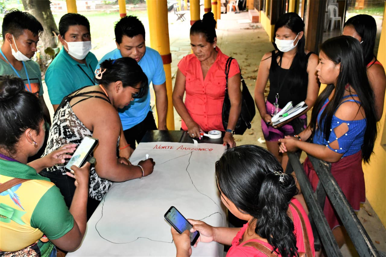Foto: CEJIS En grupp människor står runt ett bord med ett stort pappersark på, som de skriver på.
