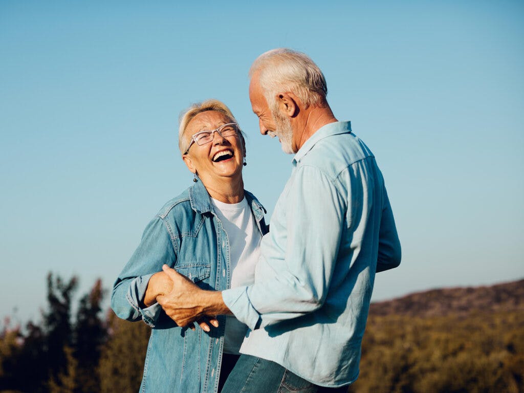 Ett äldre skrattande par i utomhusmiljö