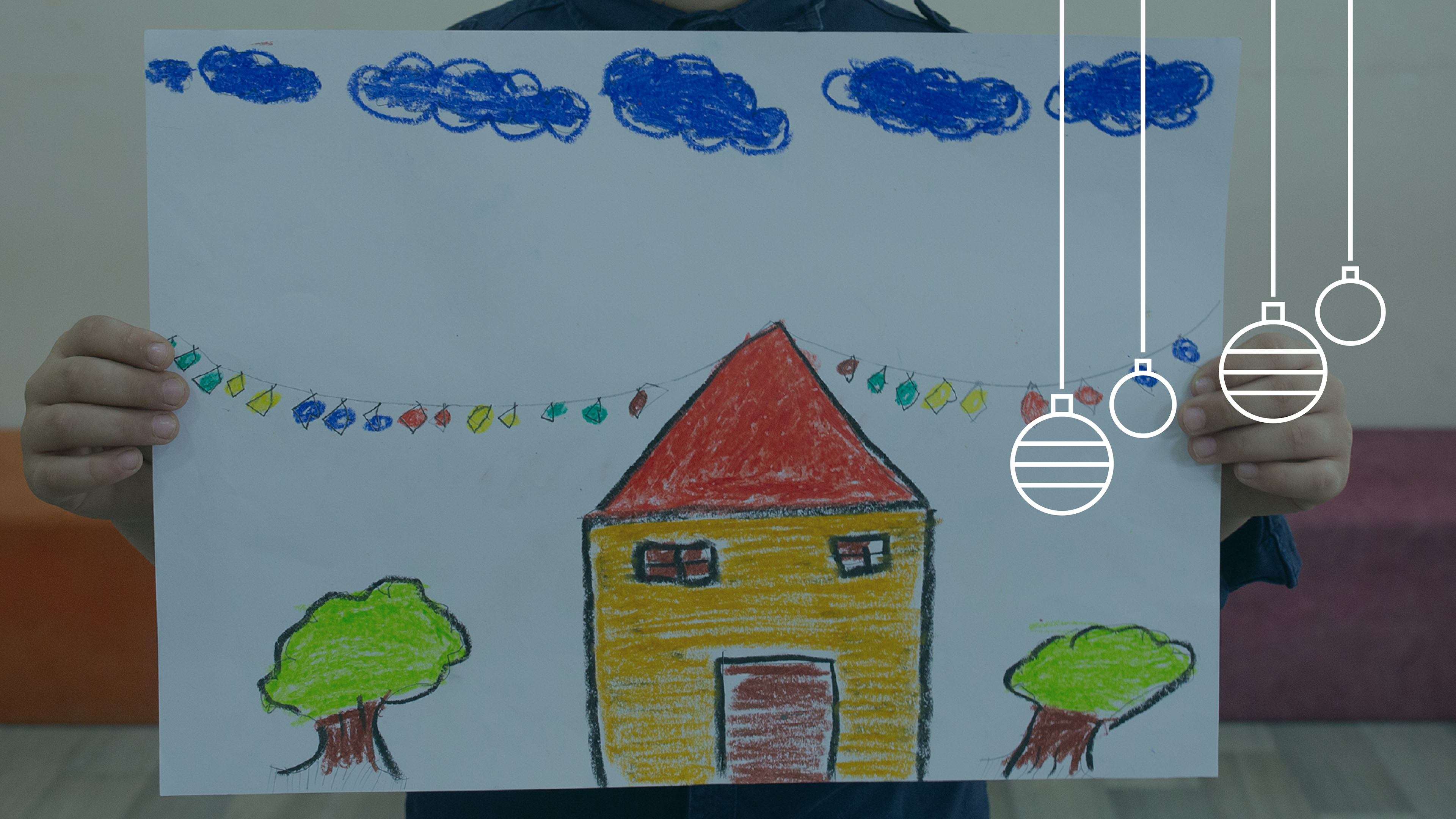 Ett par barnhänder håller upp en teckning av ett gult hus.