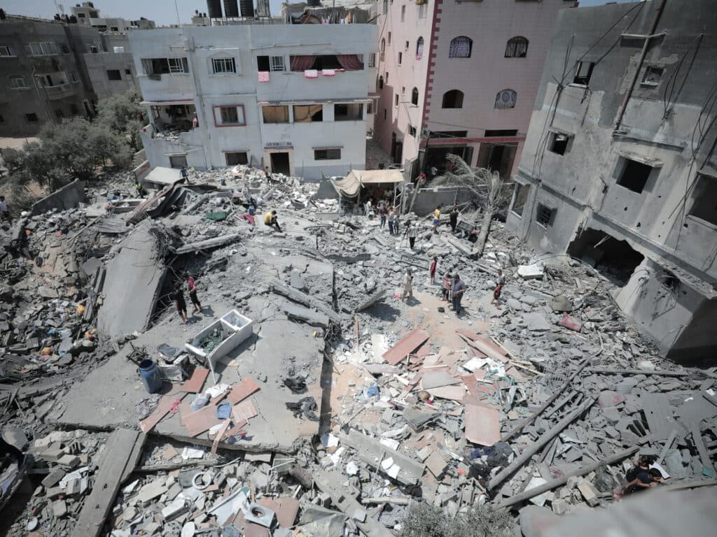 En bild av husruiner och några människor som står i ruinerna.