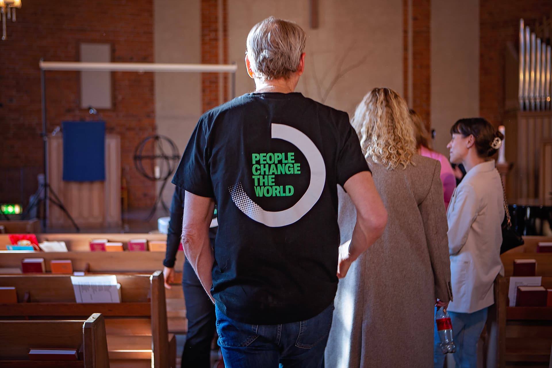 Bild tagen i en kyrka, i kyrkan står en man med Diakonias logga och trycket "People Change the World"
