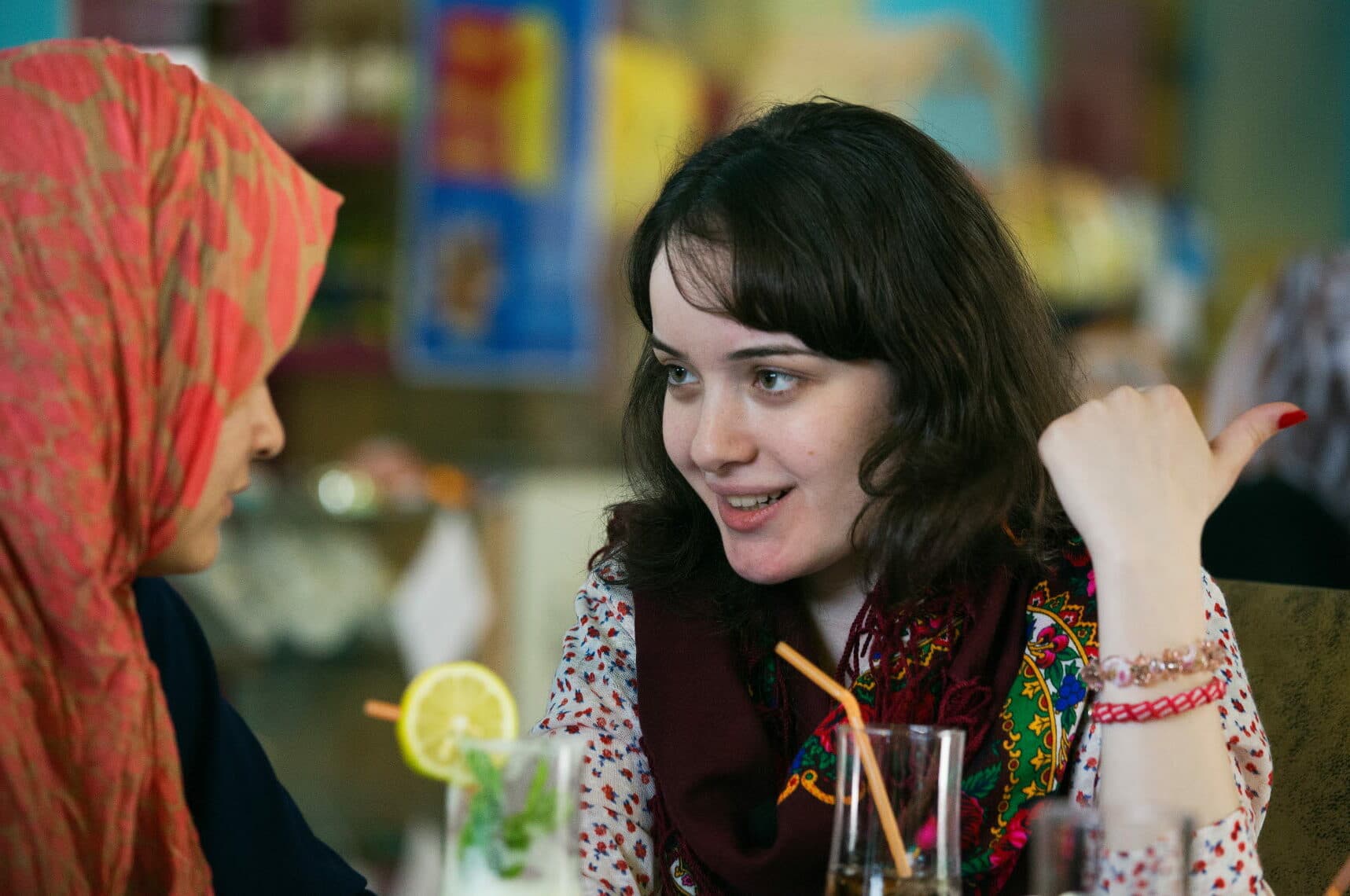 Two young women talking to each other in a cafe.