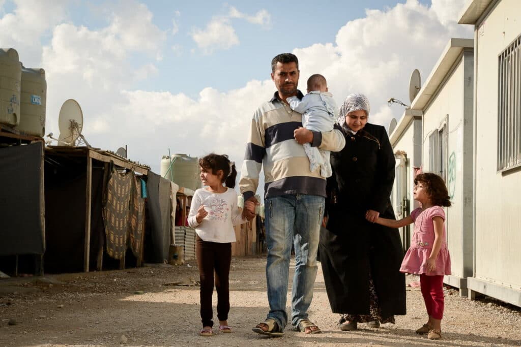 A family walking through the street in a camp of barracks.