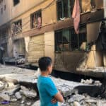 A man in front of a building looking at the damaged caused by an explosion.