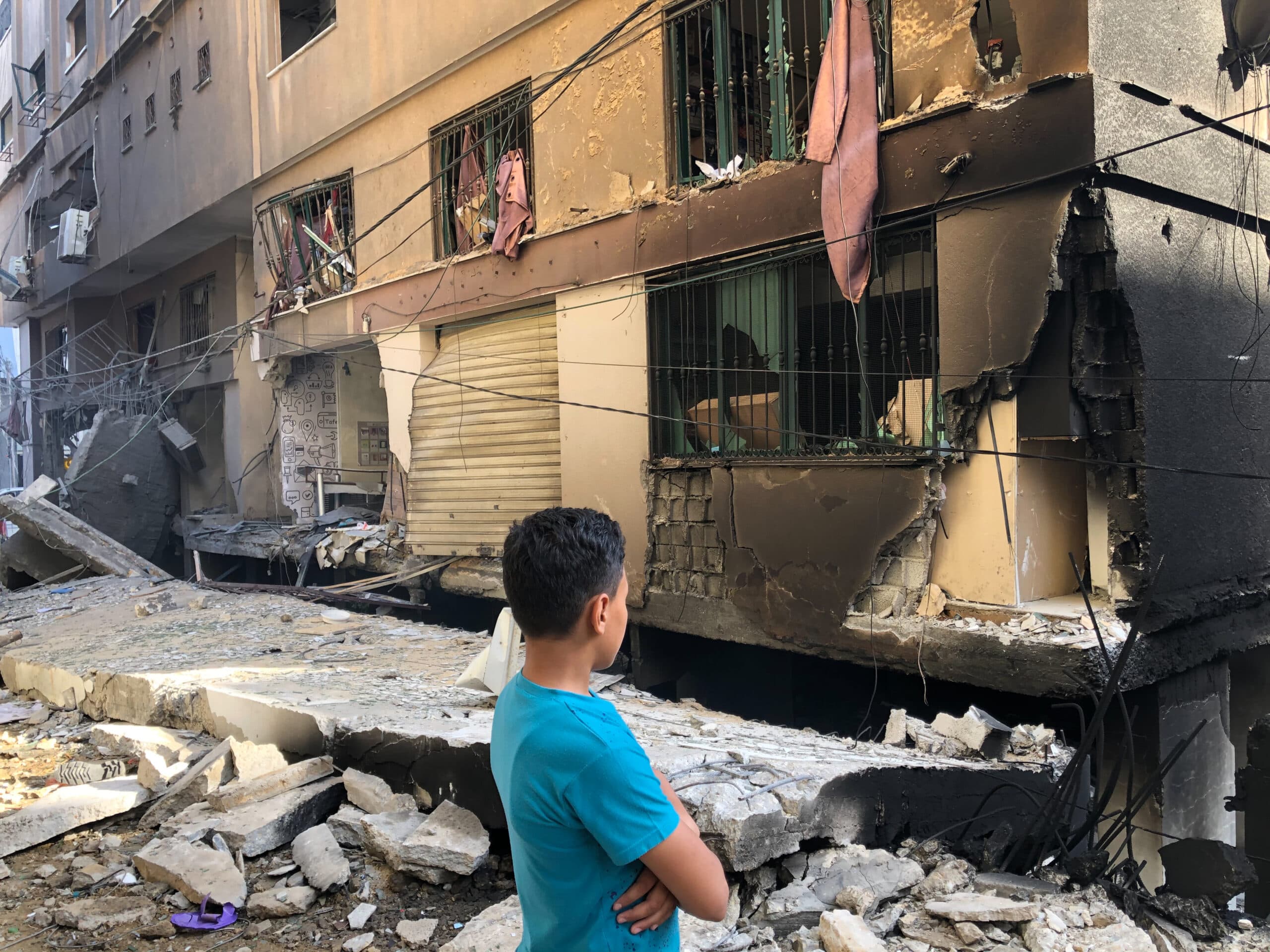 A man in front of a building looking at the damaged caused by an explosion.