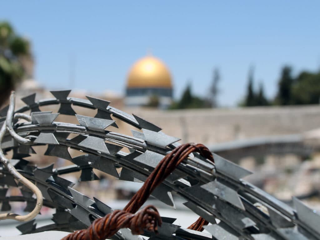 Barbed wire and in the background the golden dome of the Dome of the Rock in Jerusalem.