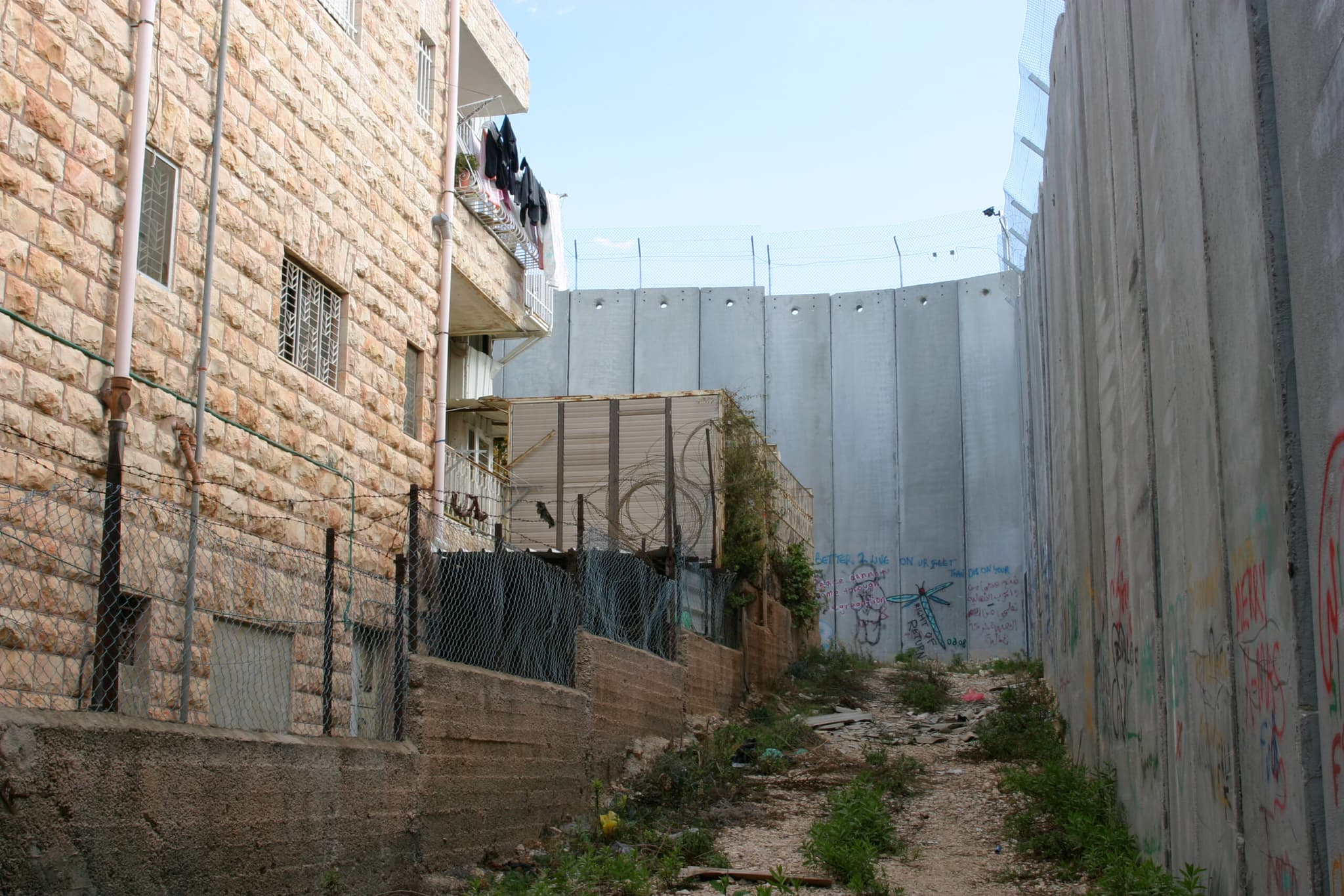 A high concrete wall next to an appartement building.