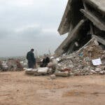 A man and a woman in front of destroyed building.