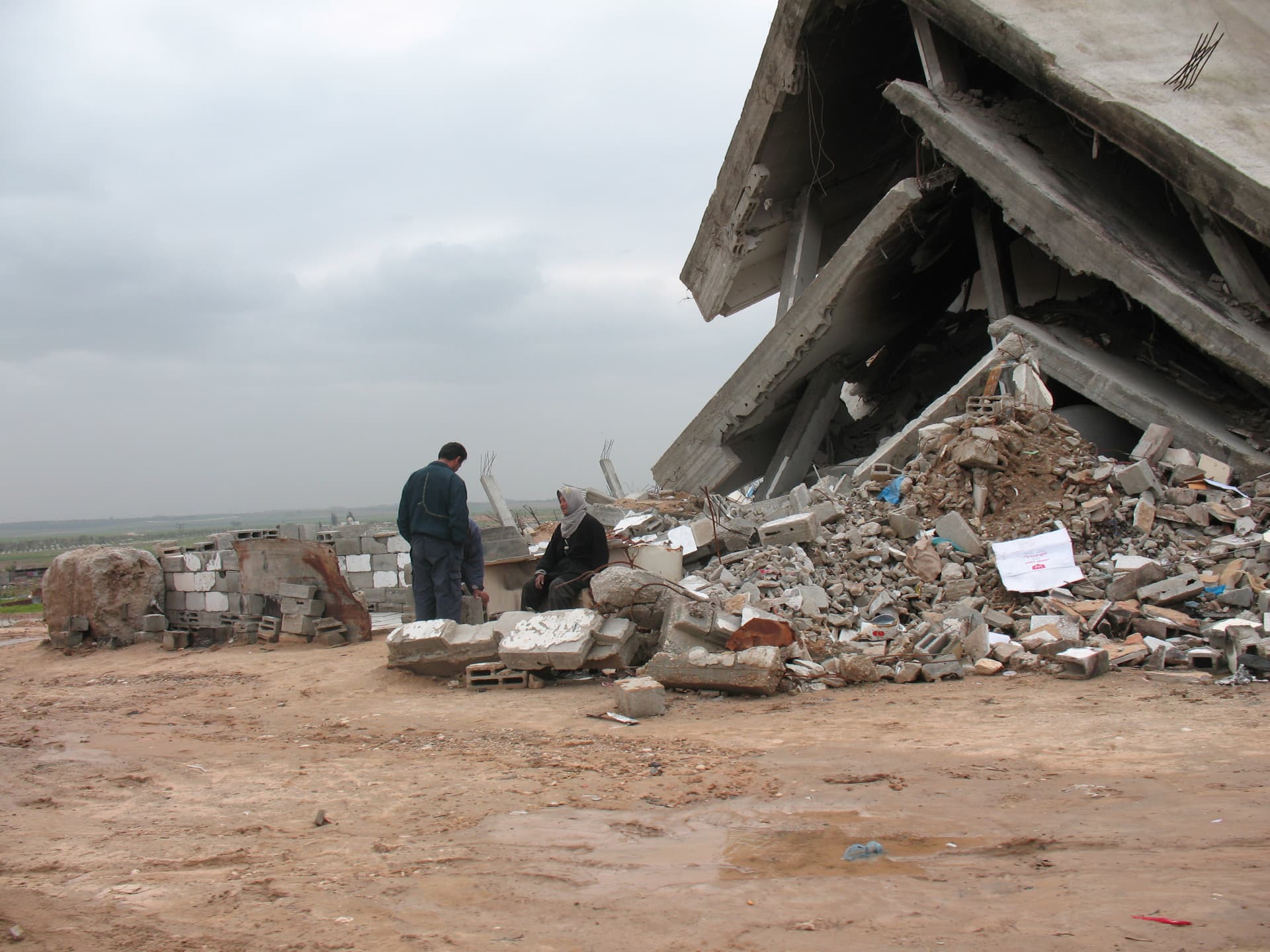 A man and a woman in front of destroyed building.