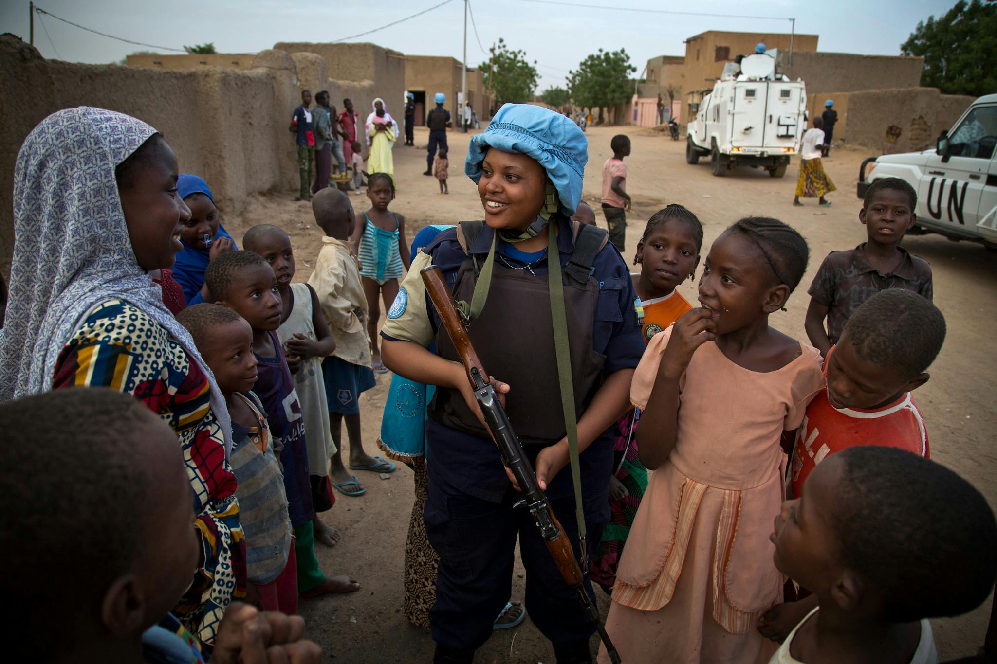 A female soldier with a blue helmet surrounded by women and girls.
