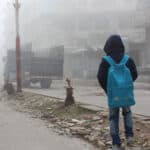 A child watching a truck that carries humanitarian aid.