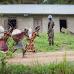 A peacekeeper stands guard as a group of women passes.