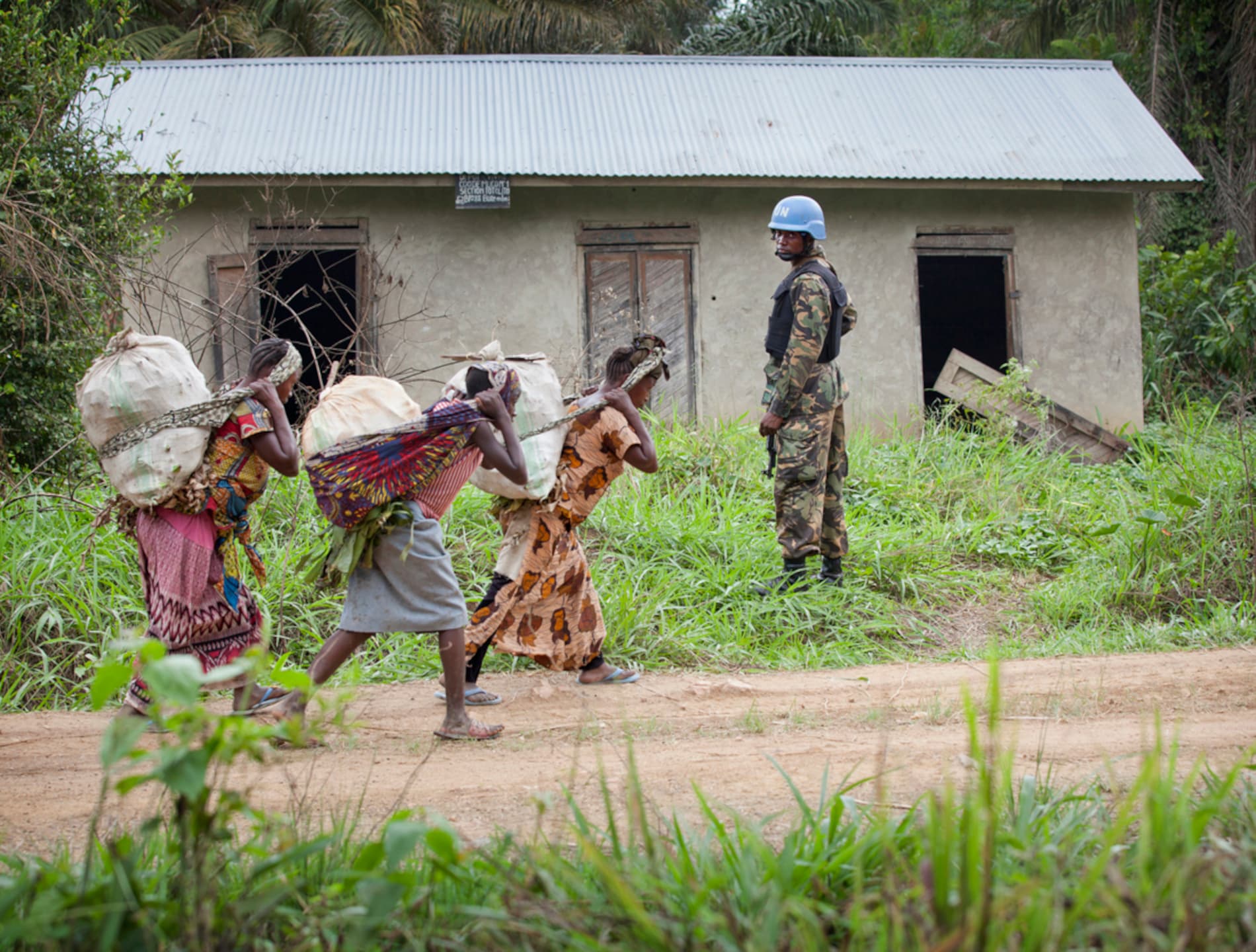 A peacekeeper stands guard as a group of women passes.