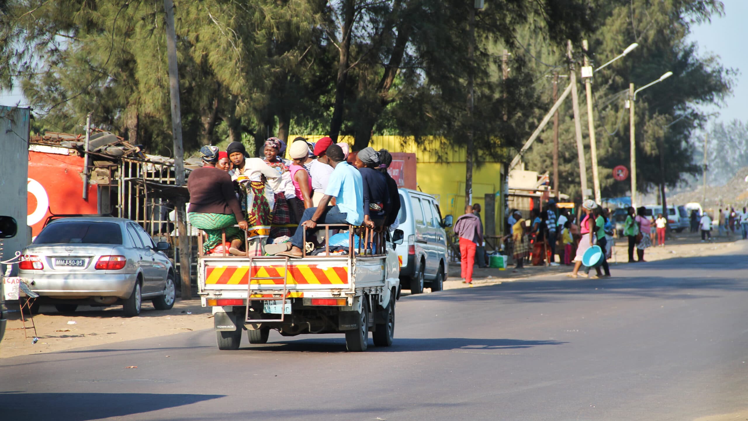 A truck driving on a road, with a group of people on it.