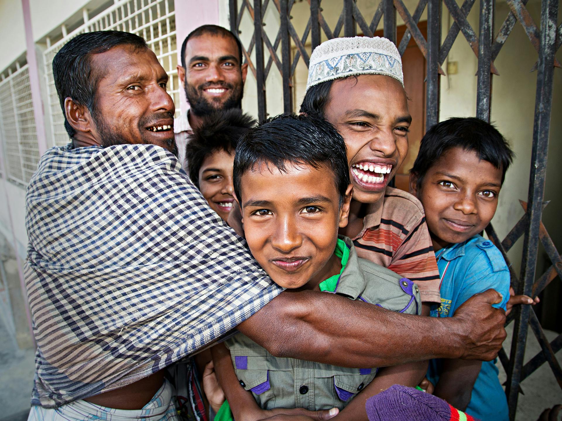 A group of adults and children hugging and smiling.