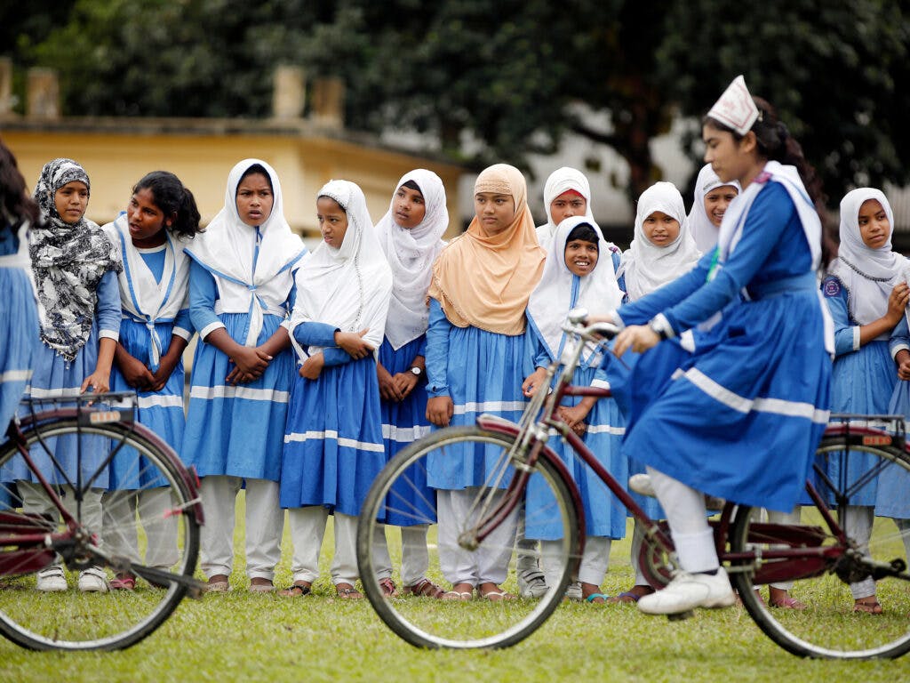 A big group of girls riding bicycles.