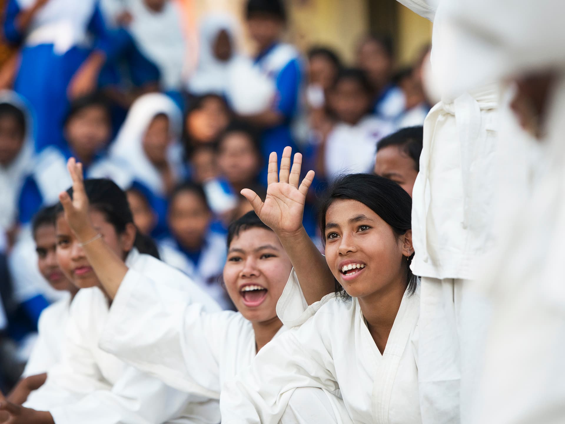 Young women in Karate suits sitting in a group cheering.