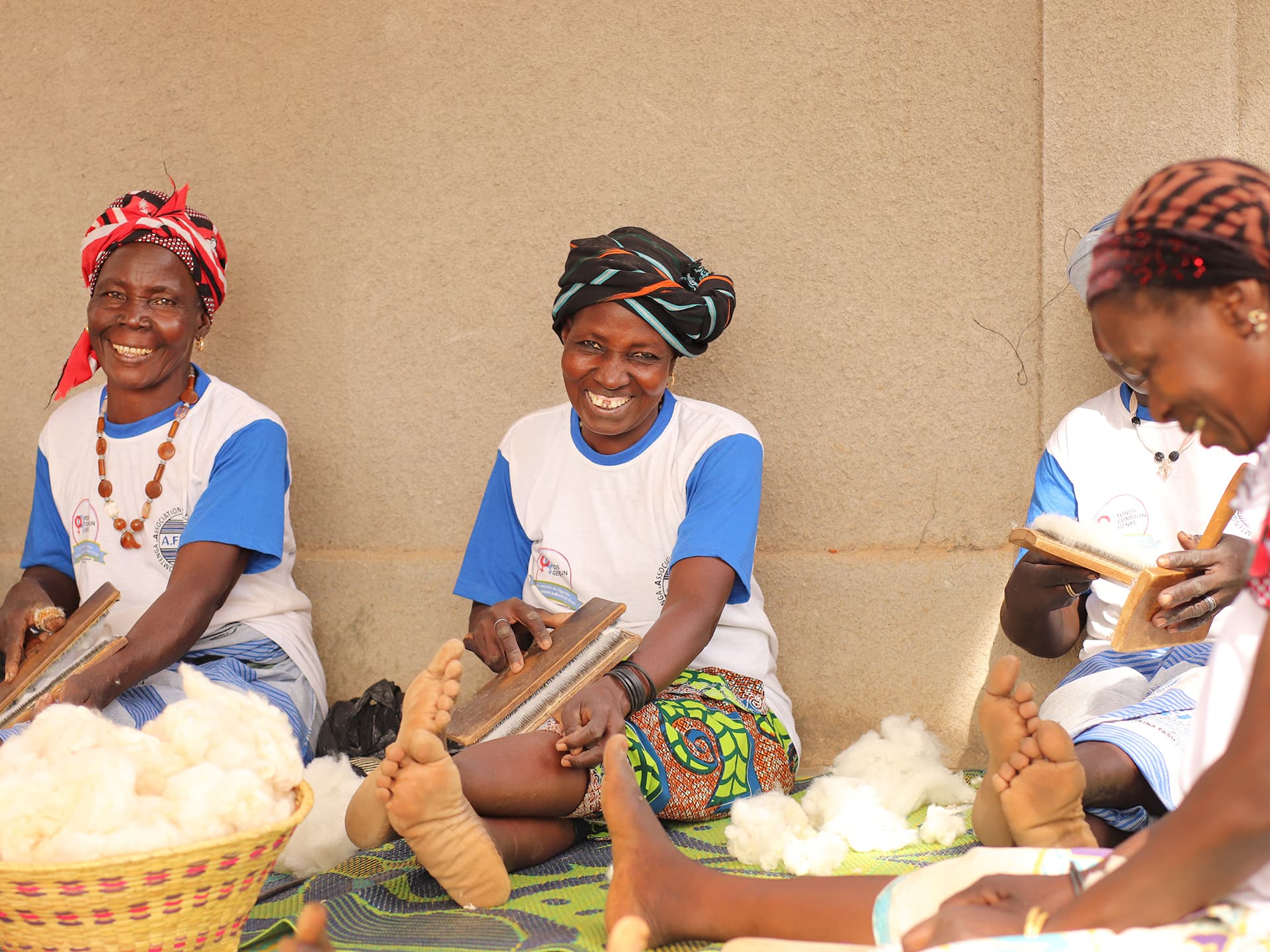 A group of women sitting on the floor weaving.