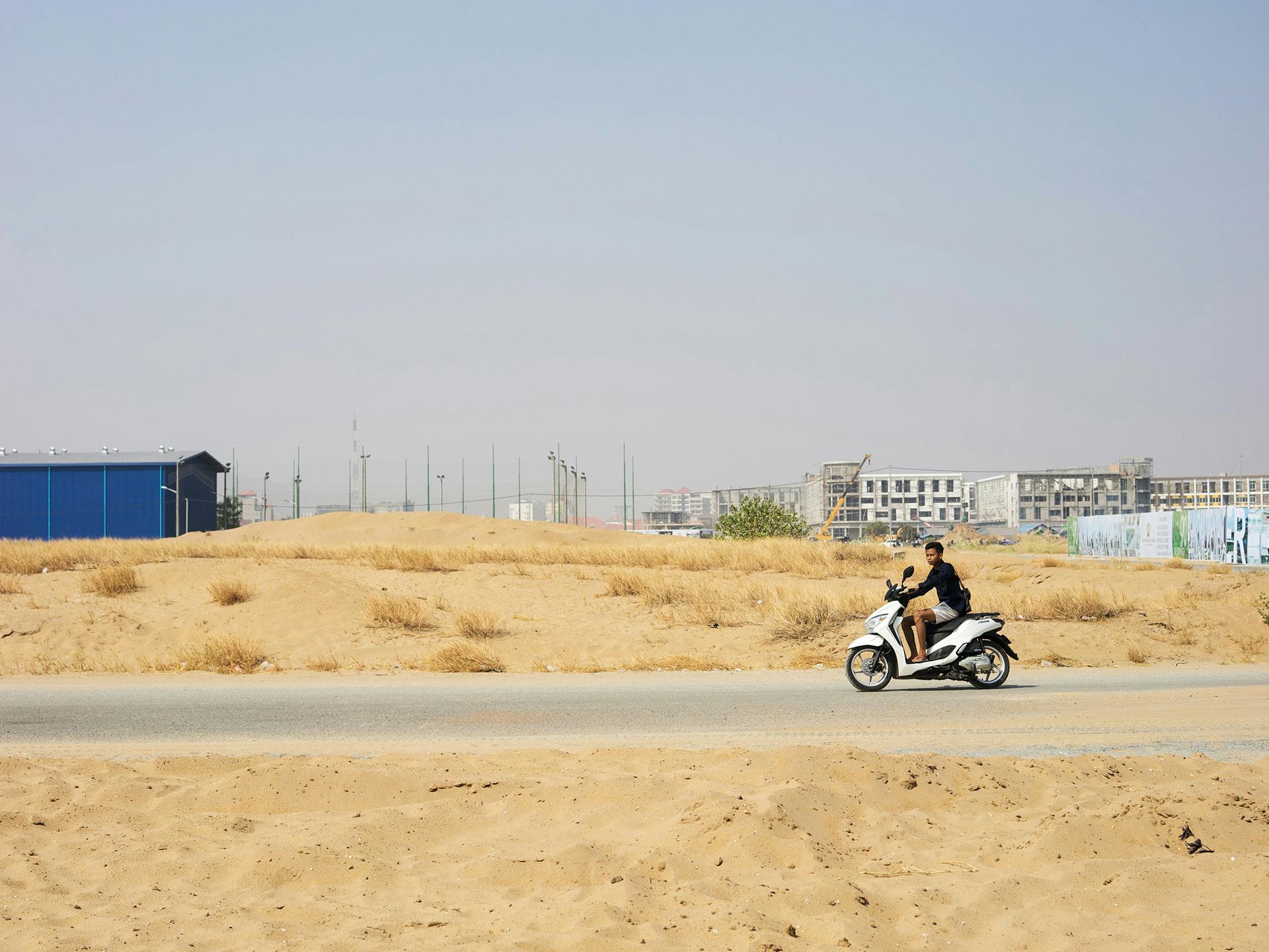 A man on a motorcycle dricing through a wide landscape.