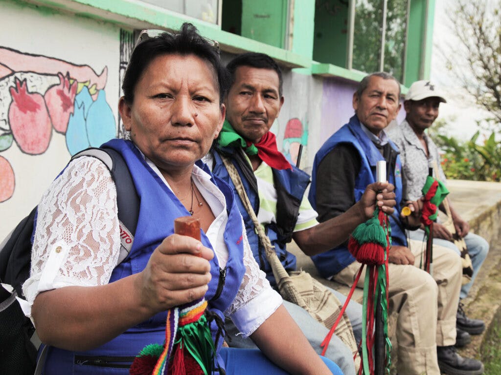 A Colombian woman looking into the camera. In the backgrund there are three men.