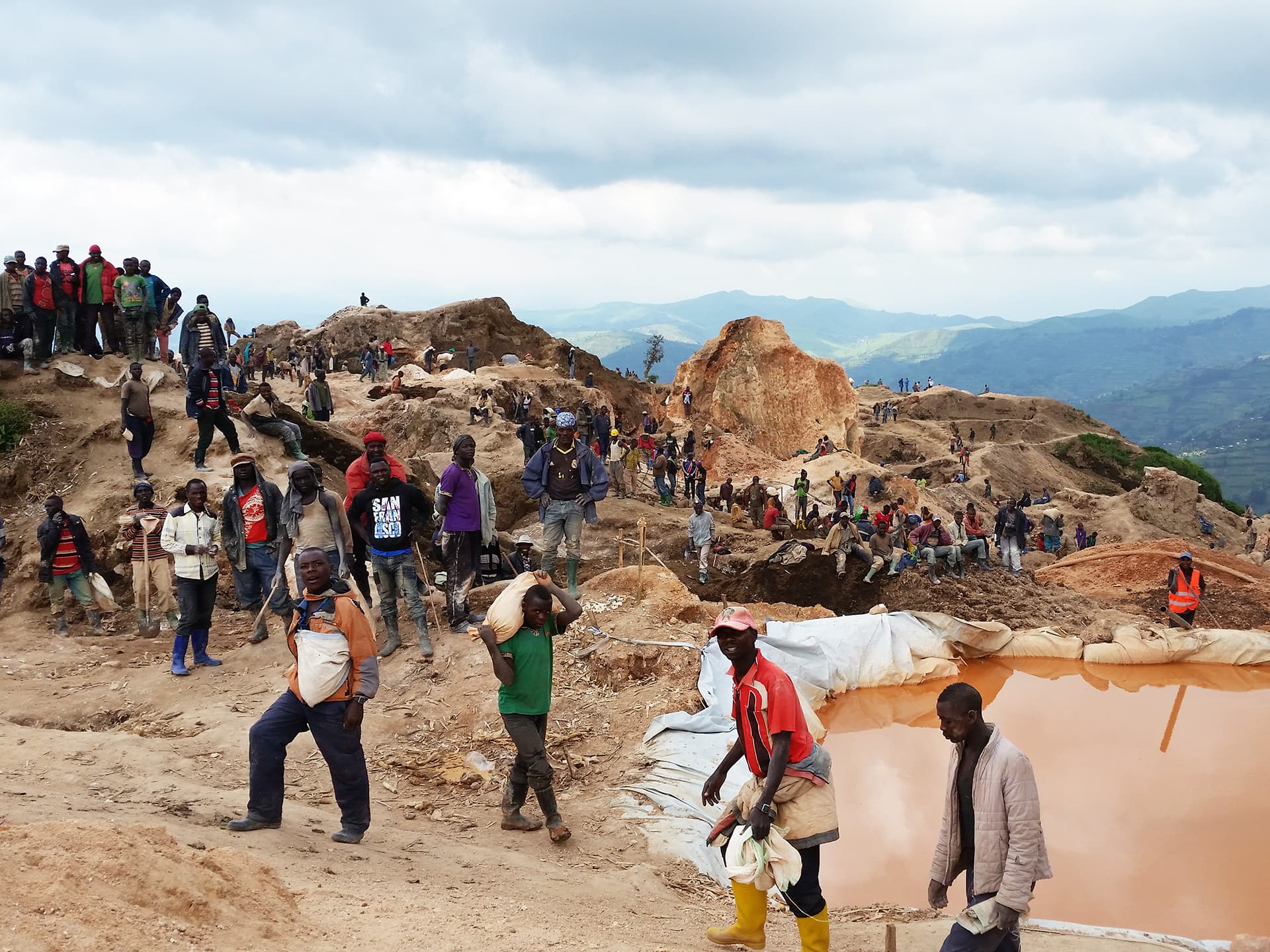 A large group of people in a field alongside mines.