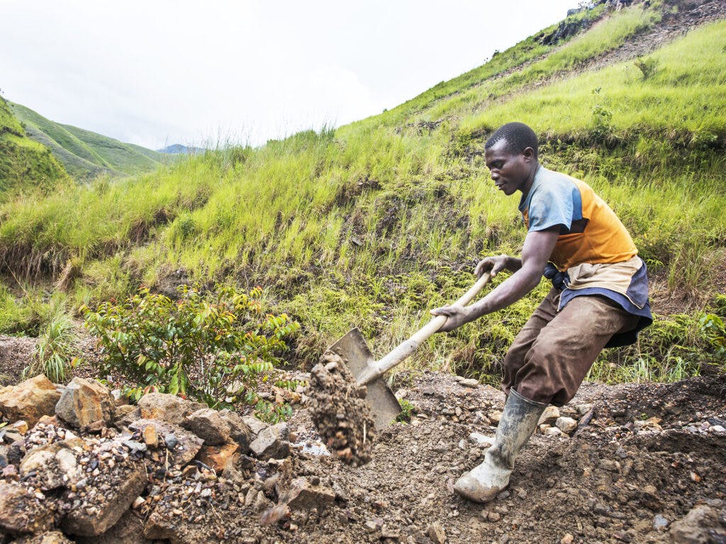 A Congolese man using a shovel in a field.