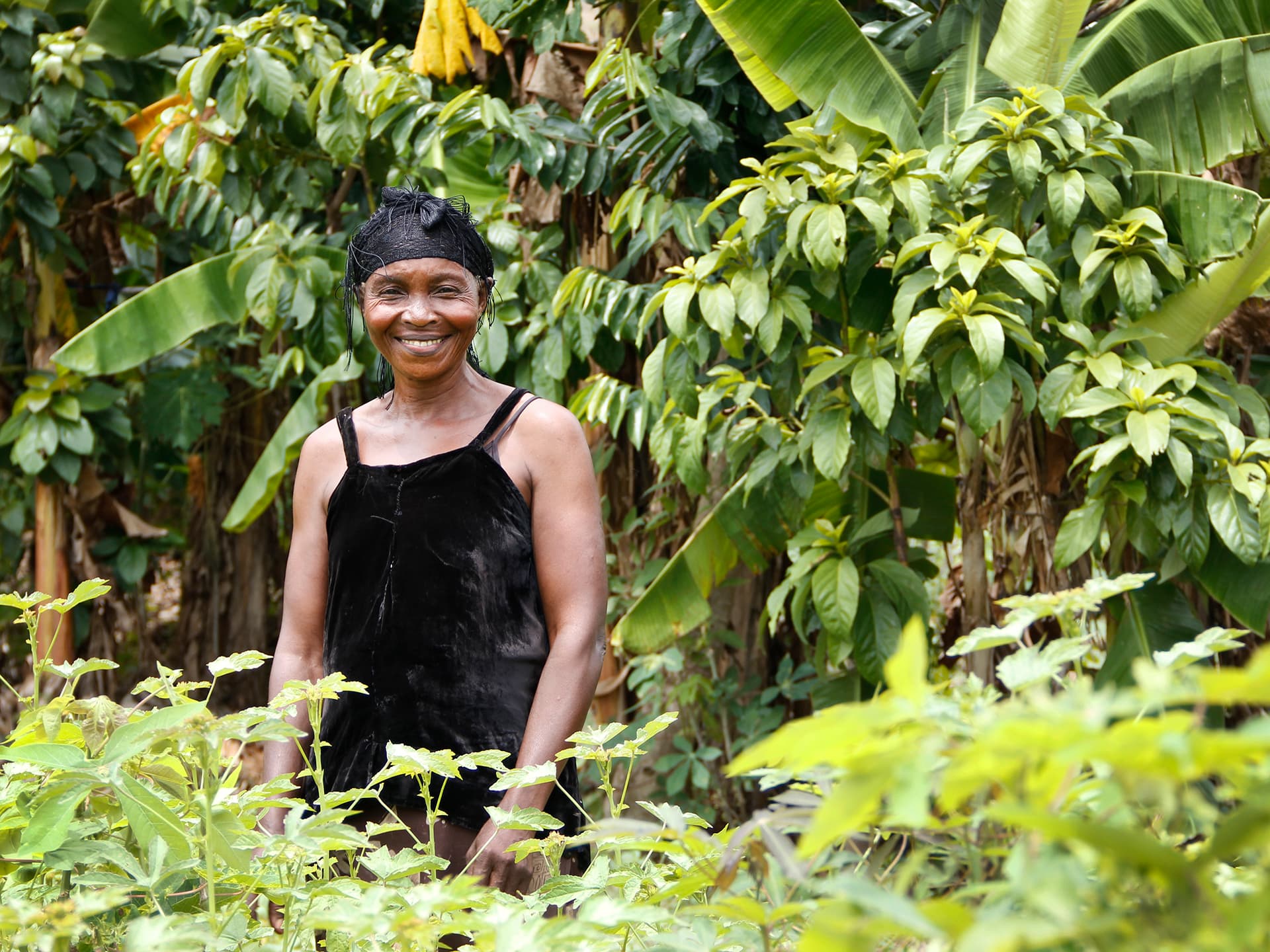 A woman standing in a green field with trees behind her.