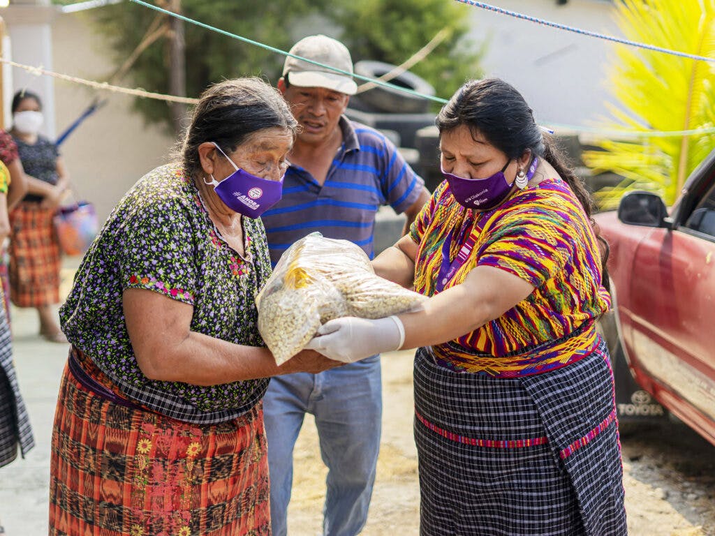 Two Guatemalan women wearing face masks handling food packages