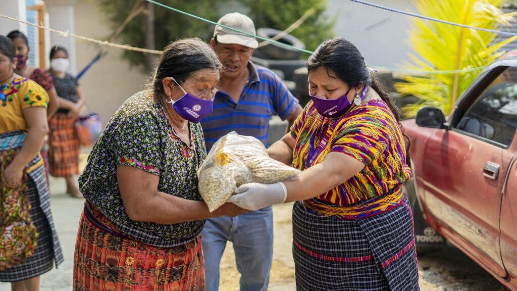 Two Guatemalan women handing over food packages.