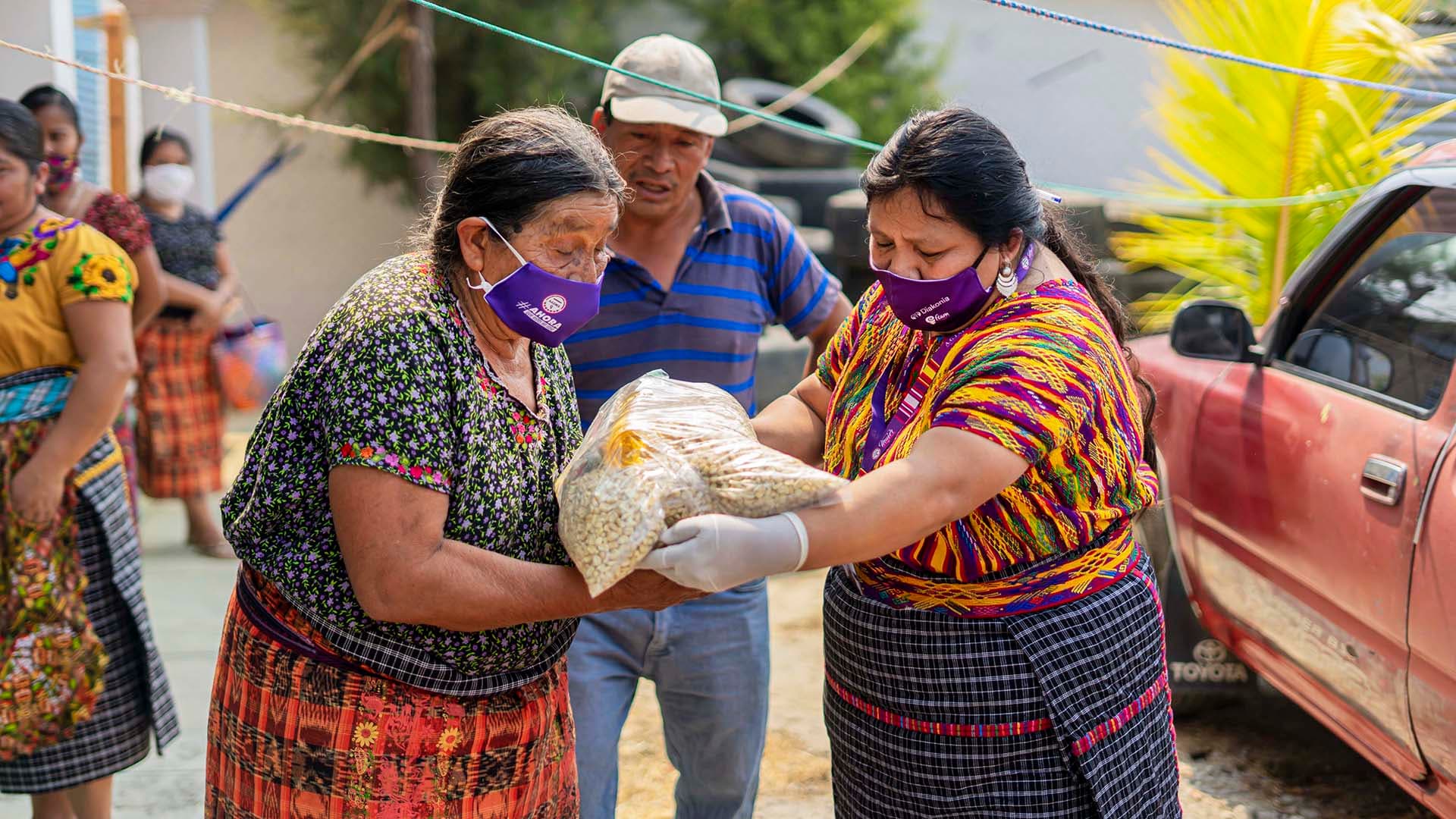 Photo: AGIMS Two Guatemalan women handing over food packages.