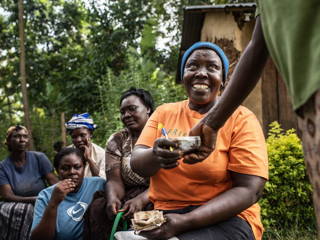 A hand holding money reaching over to a woman.