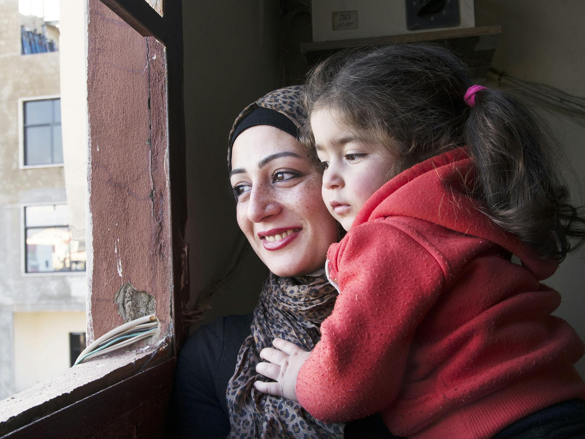 A Palestine woman and her child looking out through a window