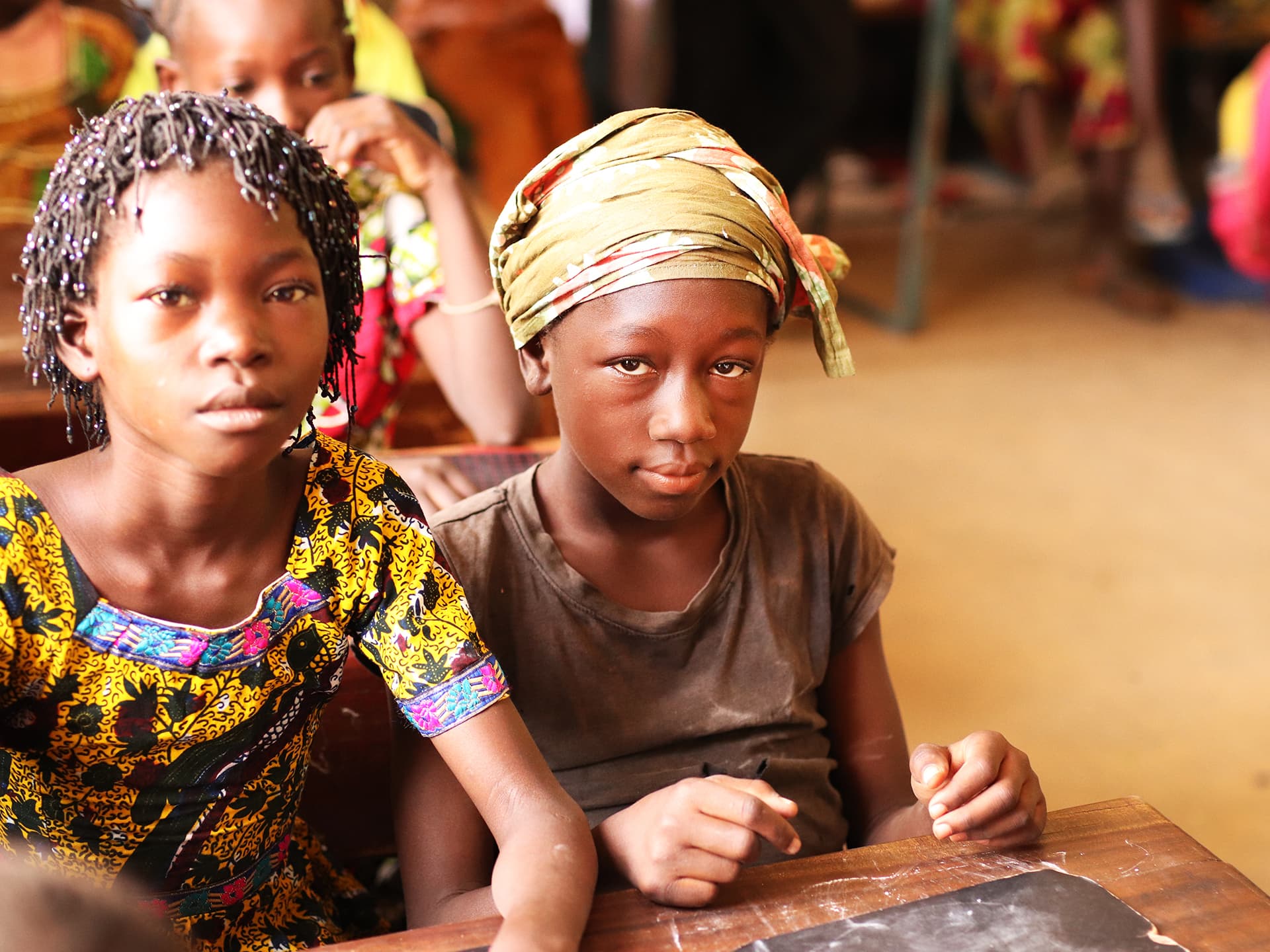 Two kids sitting in a classroom.