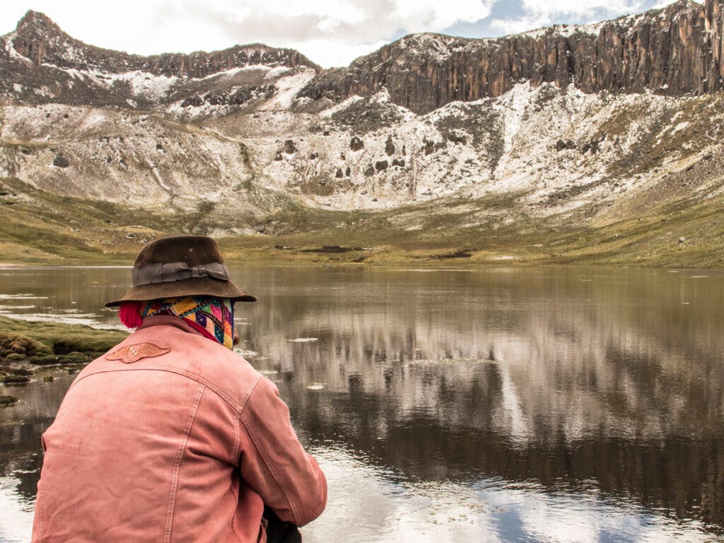 Man sitting by water in the mountains in Peru