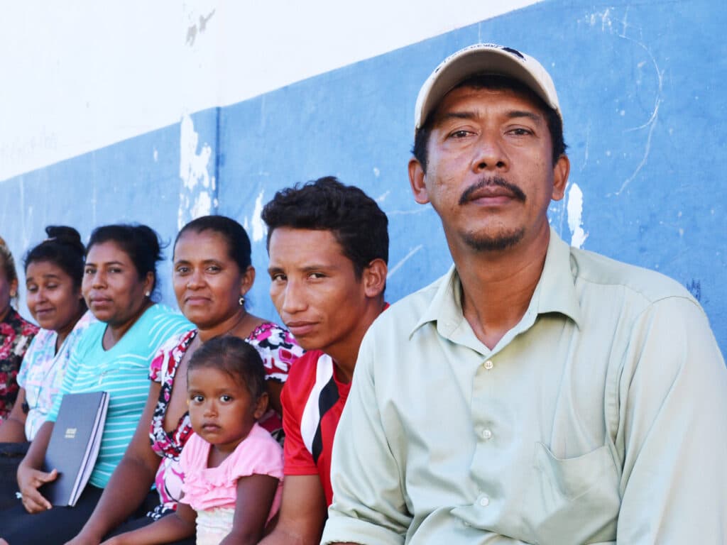 Portrait of a man looking into the camera, in the background there is a group of people.