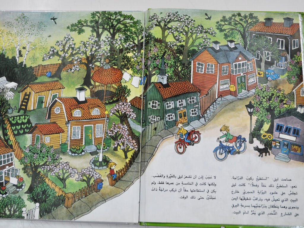 An open children's book with colorful illustrations and text in Arabic.
