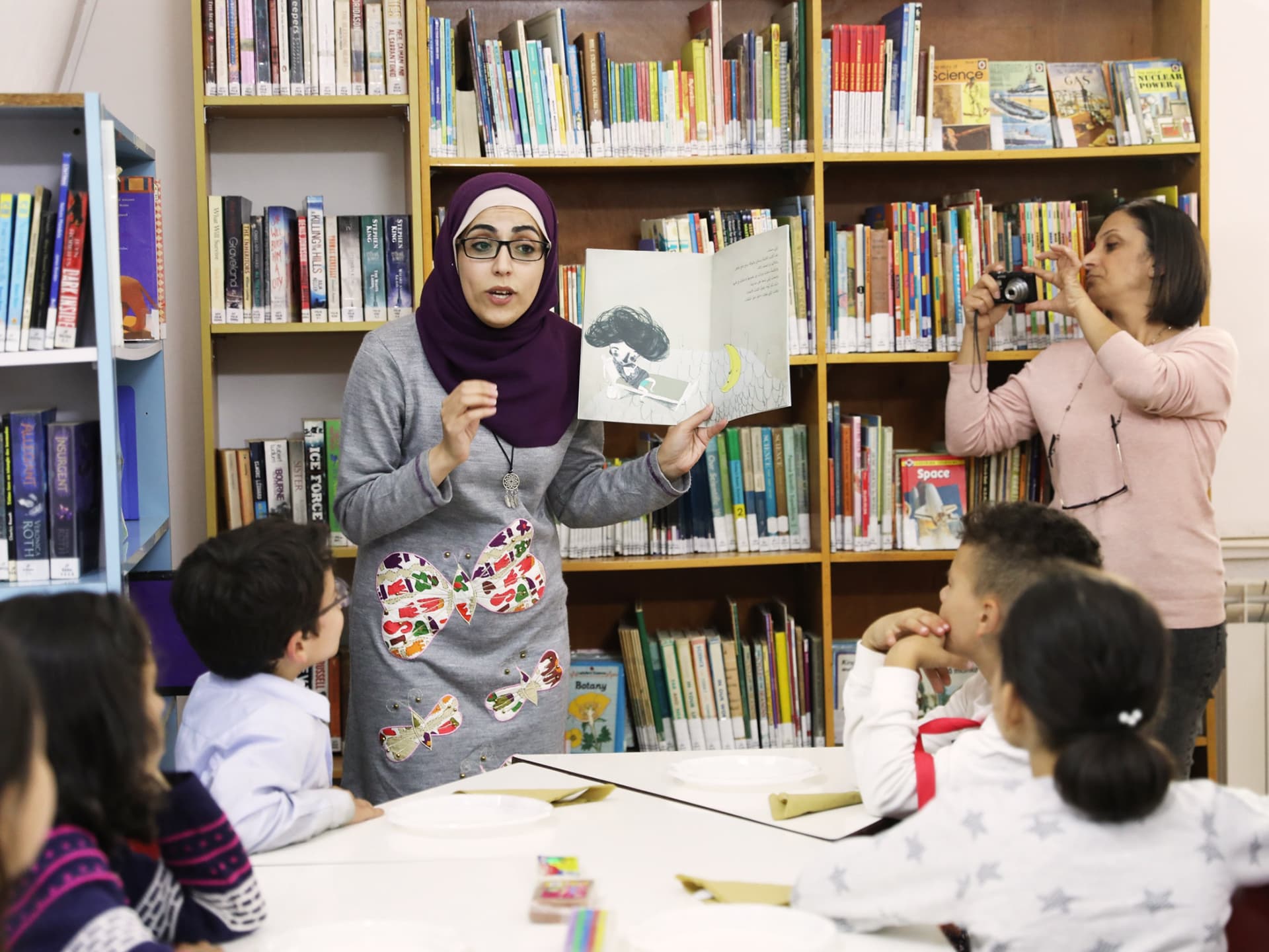 Photo: Diakonia A teacher reading a childrens book to a group of children in a library