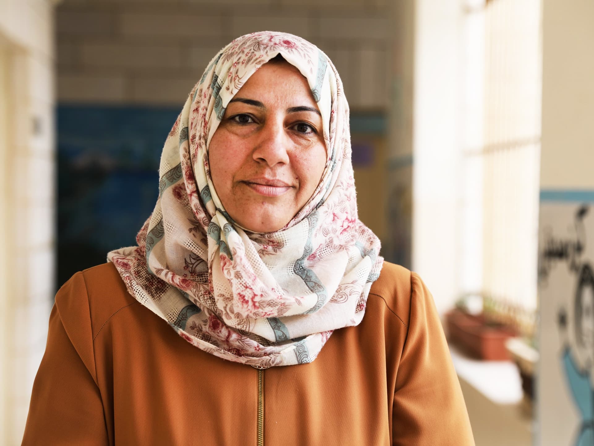 A woman looking into the camera, standing in a school corridor