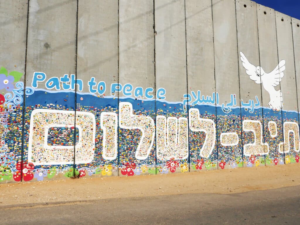 Image of a concrete wall with a mural that says "Path to peace".