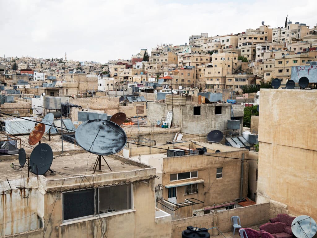 A view of a refugee camp in Palestine, with a lot of houses and a hill.